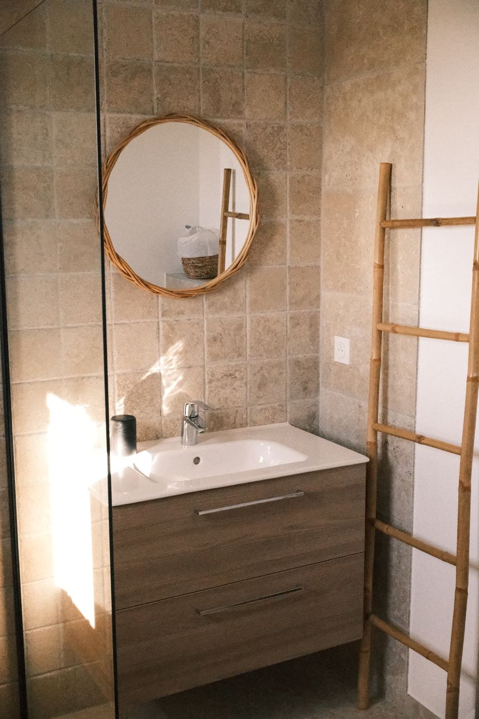 Salle de bain privative avec miroir en rotin et pierre naturelle