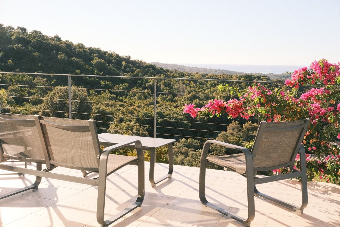 Terrasse avec fauteuils, bougainvilliers et vue sur la mer